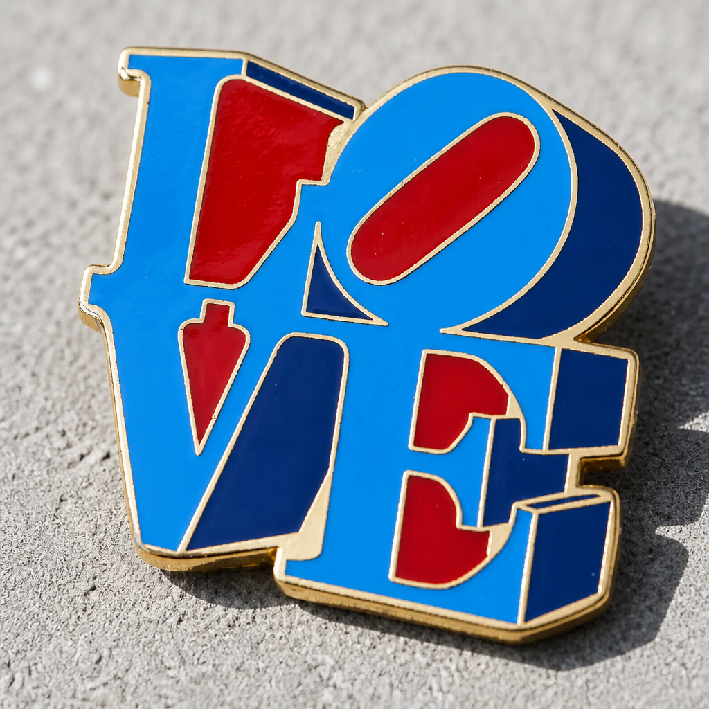 Officially licensed Robert Indiana LOVE enamel pin featuring the iconic red and blue LOVE artwork with polished gold plating on a concrete surface