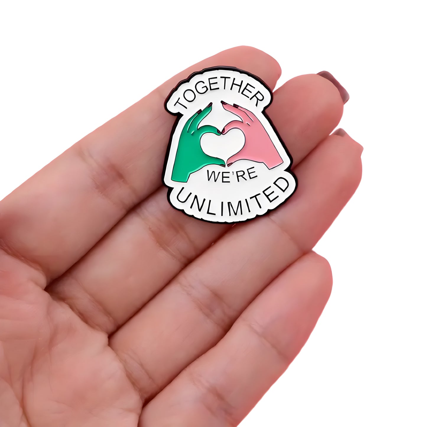 Together We’re Unlimited enamel pin with pink and green hand heart design inspired by musical theater fandom held in a hand