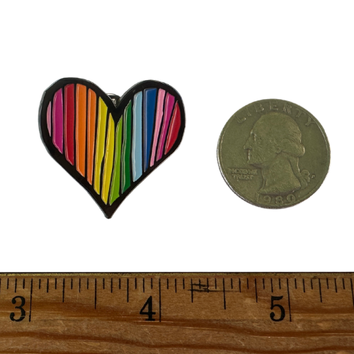 Textured Rainbow Heart enamel pin with colorful striped Pride-inspired design next to a coin and ruler for size reference