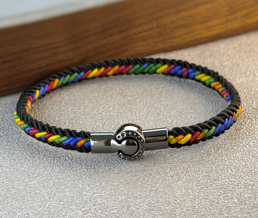 Black woven rope bracelet with rainbow threading and stainless steel magnetic clasp on a neutral background