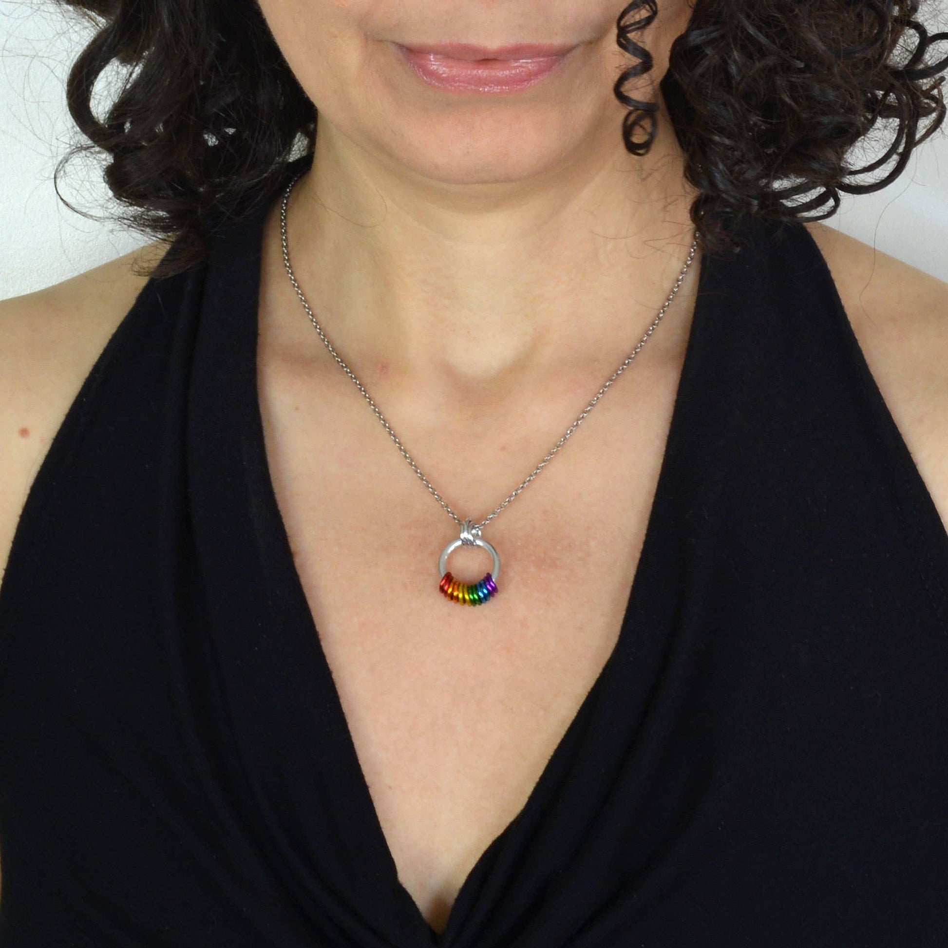 woman wearing a Handcrafted LGBTQ+ rainbow minimalist coil fidget necklace featuring twelve free-spinning aluminum rings on an adjustable stainless steel chain.