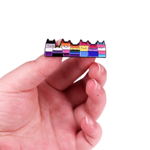 Long enamel pin featuring seven cats in different LGBTQ Pride flag colors held between fingers