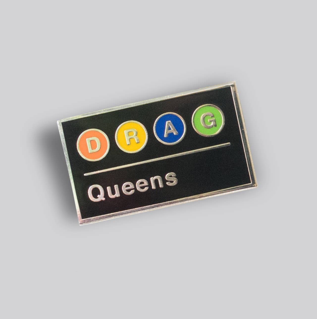 Drag Queens Subway enamel pin featuring colorful transit-style lettering on a black background