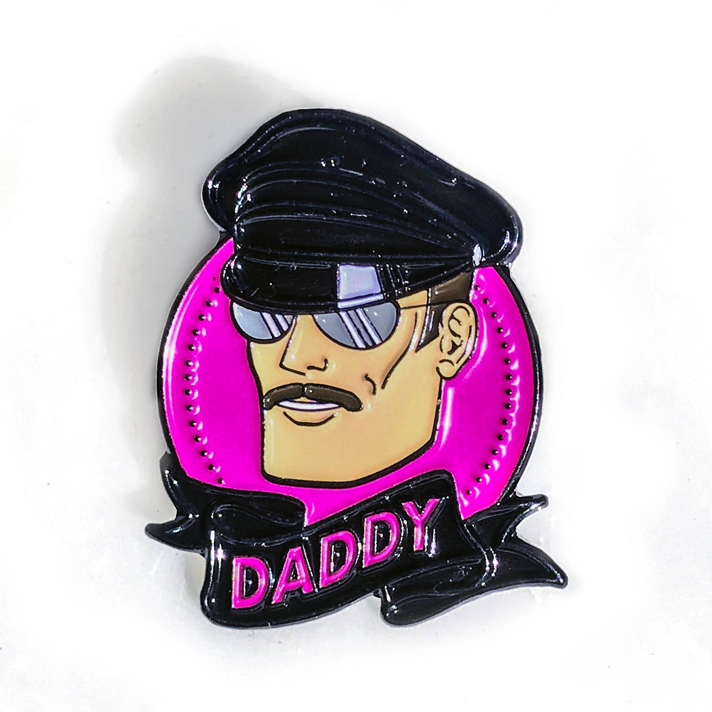 Hard enamel Daddy pin featuring a leather-inspired character wearing sunglasses against a bright pink background.