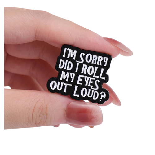 Funny Did I Roll My Eyes Out Loud enamel pin with bold sarcastic lettering held between fingers on a white background