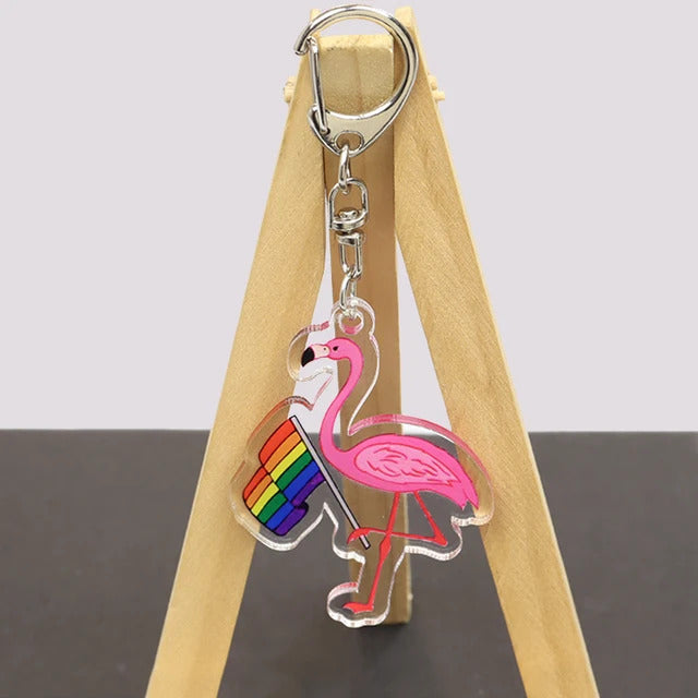 Pink flamingo acrylic keychain holding LGBTQ rainbow pride flag