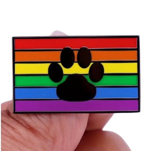 Rainbow Paw Pride enamel pin with black paw print over classic rainbow Pride flag colors held between fingers