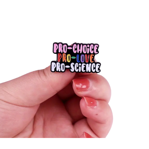 Hand holding a Pro-Choice Pro-Love Pro-Science enamel pin with colorful progressive statement lettering