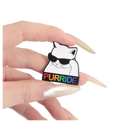 Purride Cat enamel pin featuring white cat with sunglasses and rainbow Pride lettering held between fingers on a white background