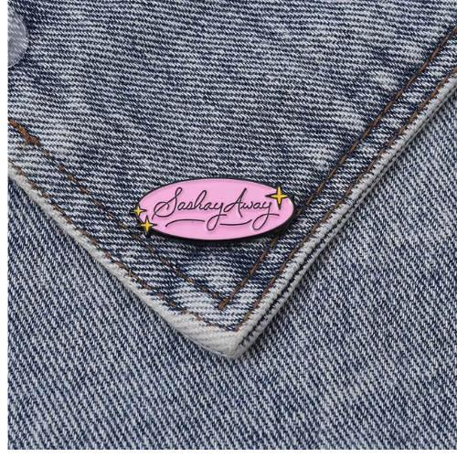 Pastel pink Sashay Away enamel pin with glamorous script lettering and star accents on a denim background