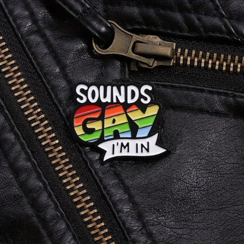Sounds Gay I’m In enamel pin with rainbow Pride lettering and funny LGBTQ phrase on a black leather jacket